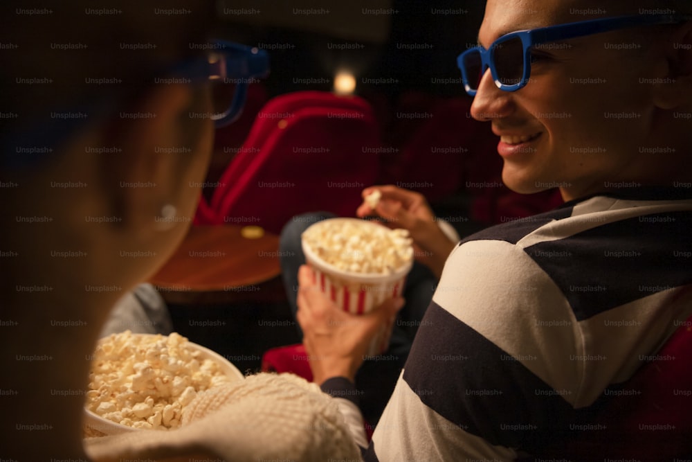 a woman sitting in a movie theater holding a bowl of popcorn