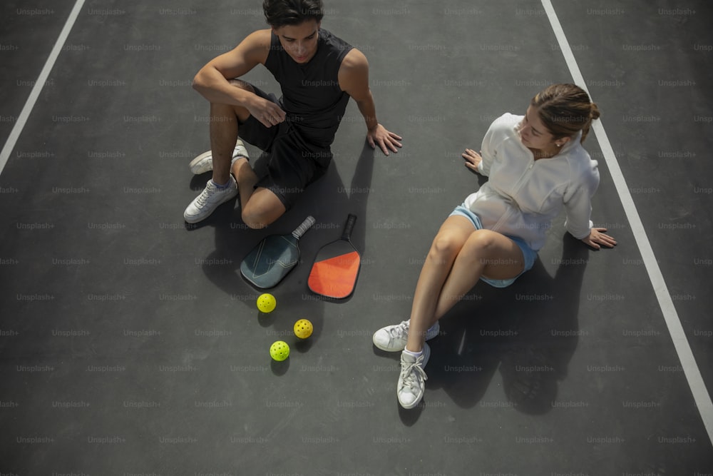 a man and a woman sitting on a tennis court