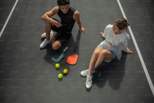 un hombre y una mujer sentados en una cancha de tenis