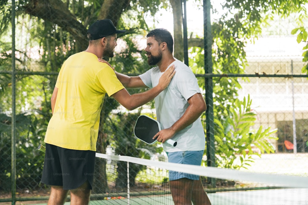 two men shaking hands over a tennis net
