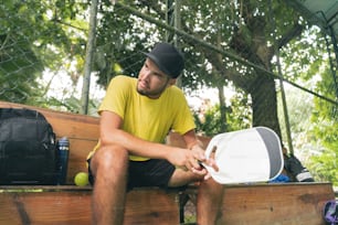 a man sitting on a bench holding a tennis racquet