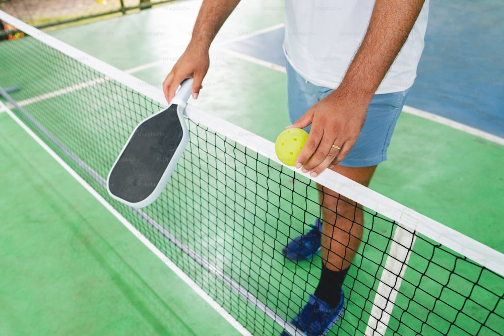 a man holding a racket and a tennis ball on a tennis court