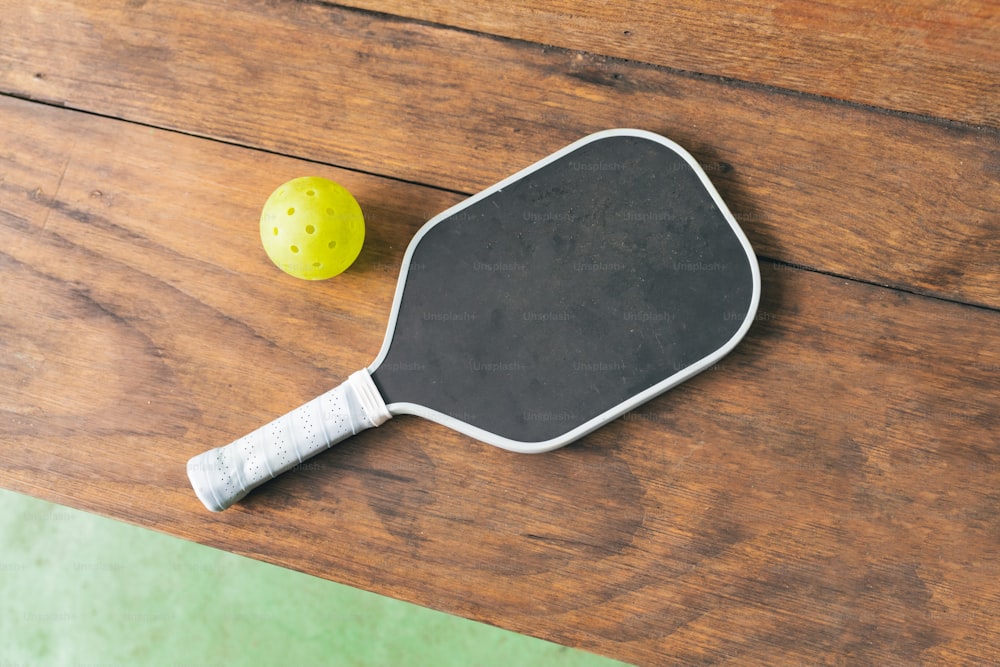 una paleta de ping pong y una pelota sobre una mesa de madera