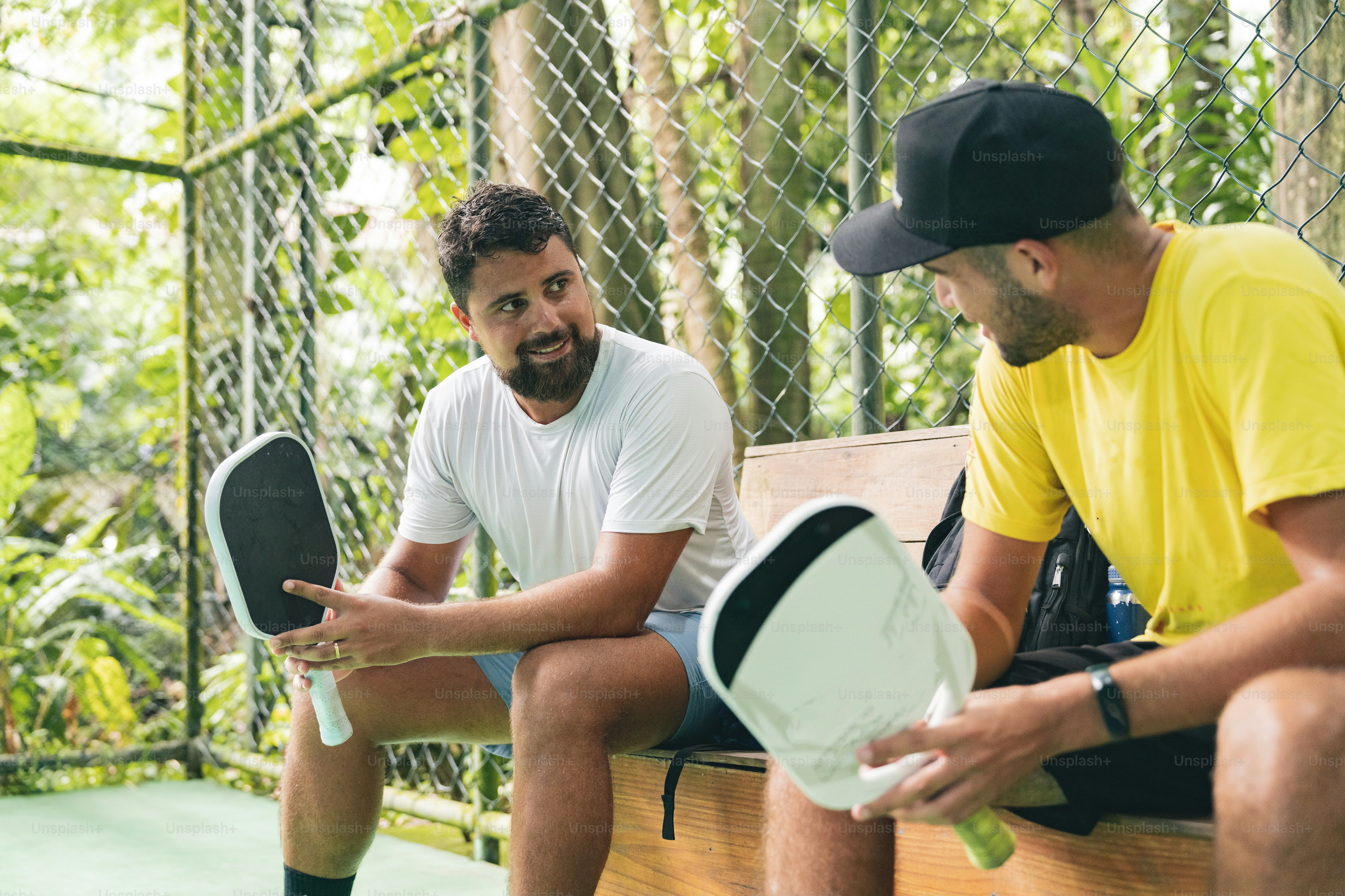 a couple of men sitting on top of a wooden bench