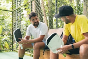 a couple of men sitting on top of a wooden bench