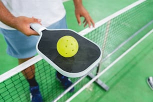 a man is holding a ping pong paddle with a yellow ball on it