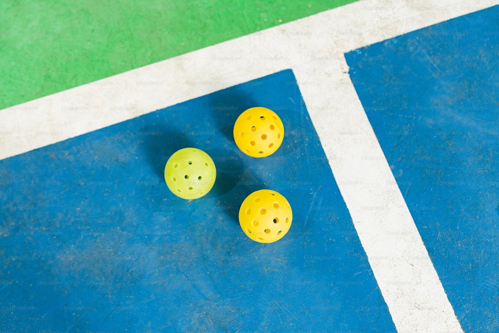 three yellow balls sitting on top of a tennis court