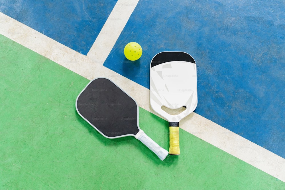 two tennis rackets and a ball on a tennis court