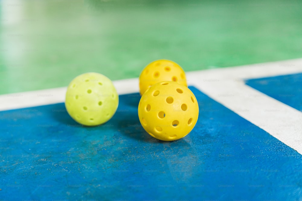 two yellow and one green balls on a blue and white floor