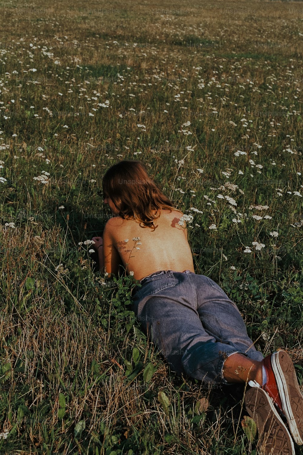 a shirtless man laying in a field of flowers