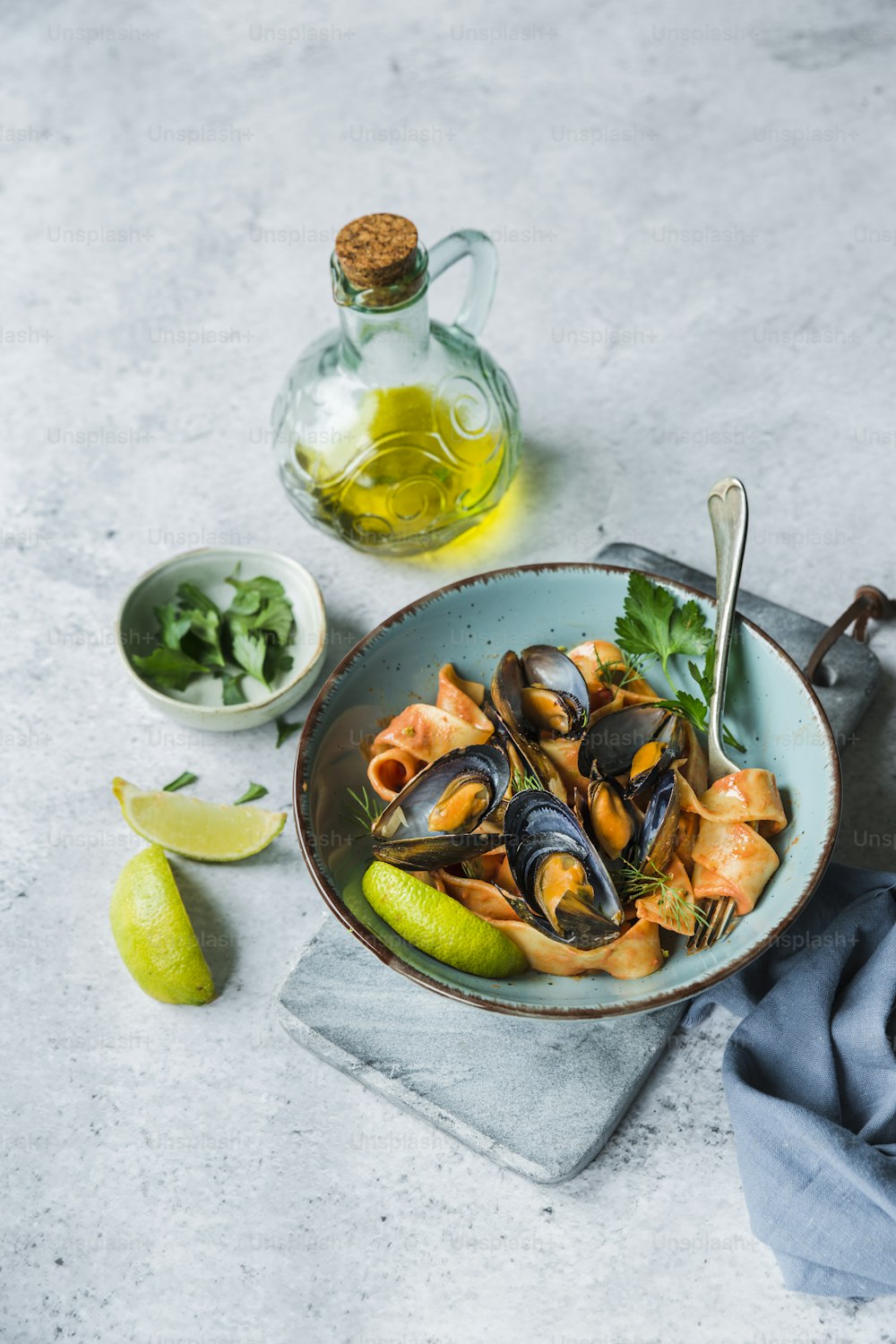 a bowl of mussels with lemon, parsley and a bottle of olive