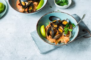 two bowls of mussels and vegetables on a table