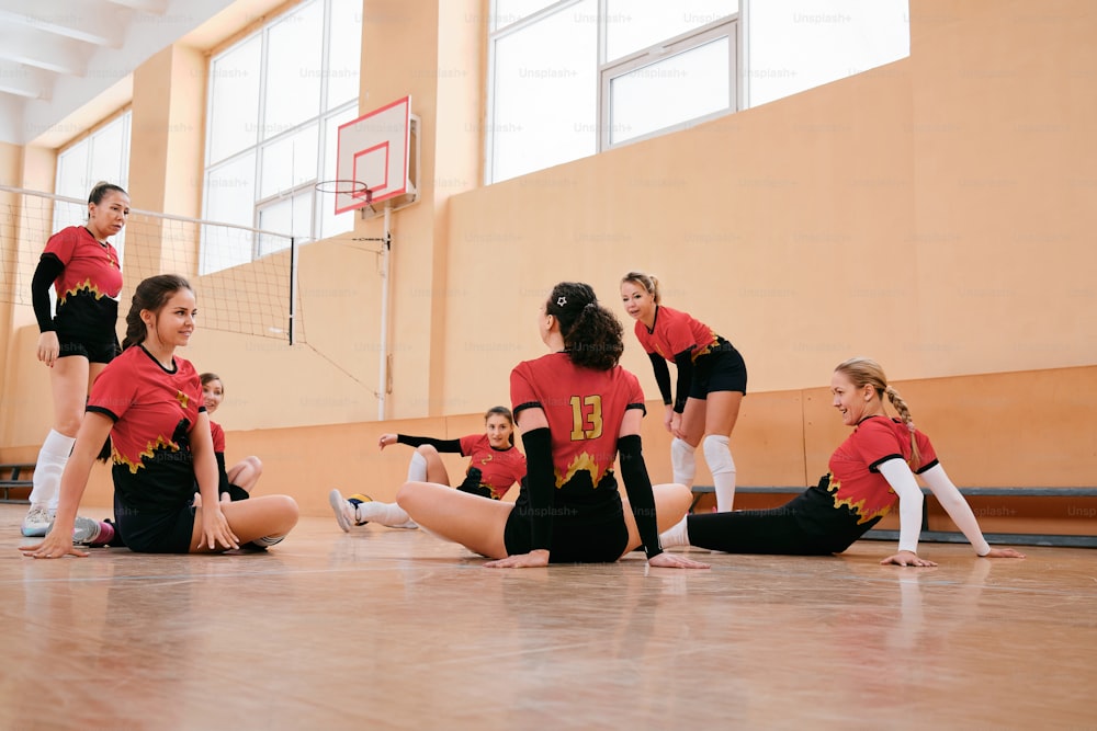 a group of cheerleaders sitting on the floor in a gym