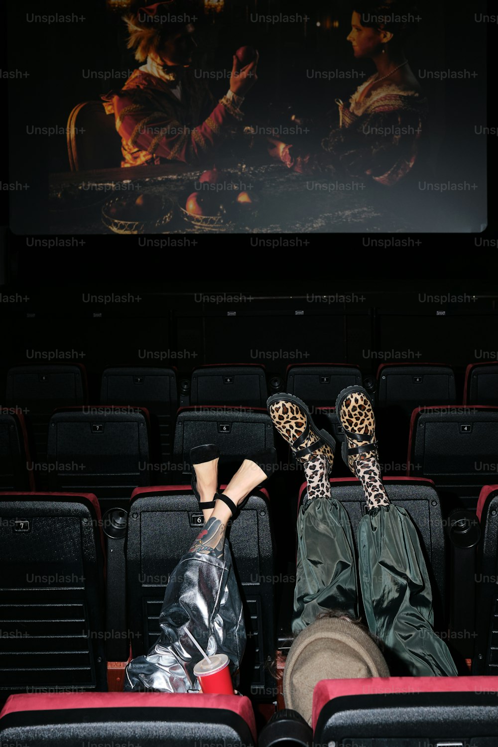 a woman laying on a red chair in front of a movie screen