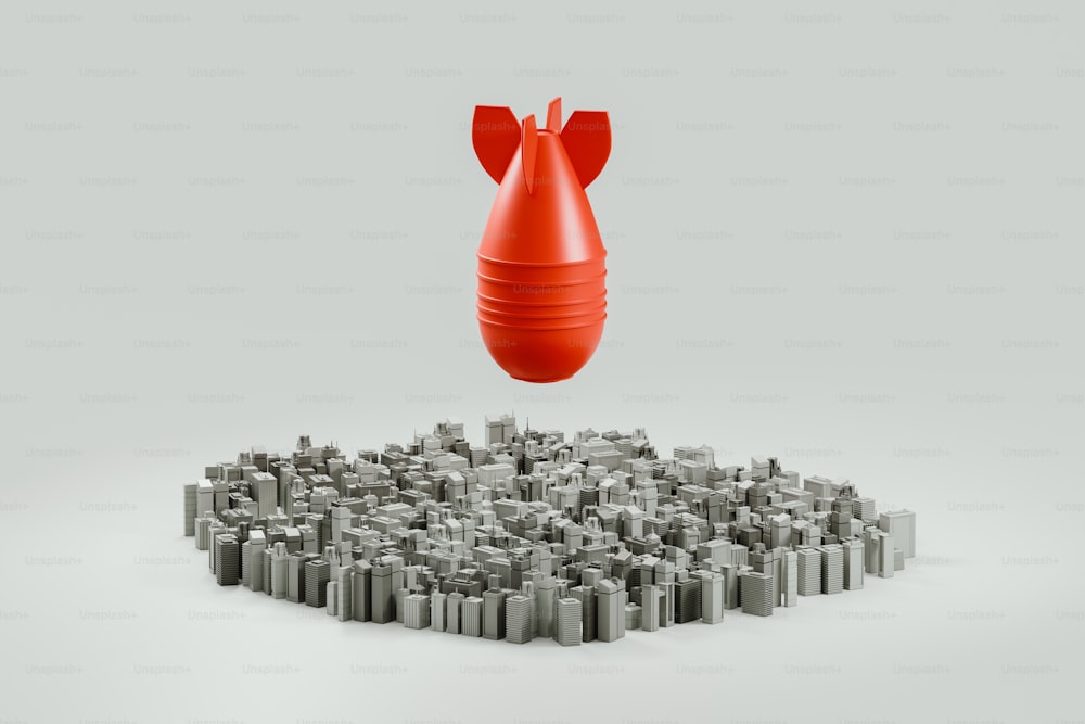 um grande objeto vermelho sentado em cima de uma pilha de objetos cinzas menores