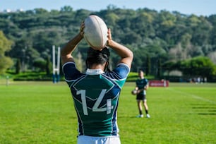 a man holding a rugby ball on top of a lush green field