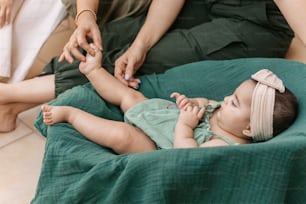 a baby laying on a bed with a woman holding her hand