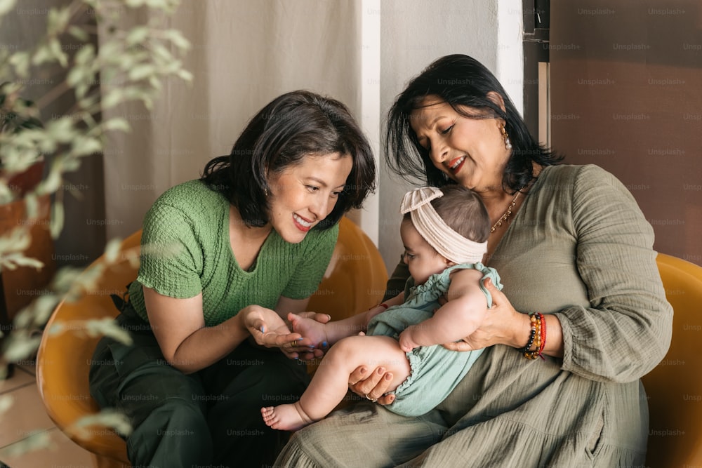 a woman holding a baby while sitting next to a woman
