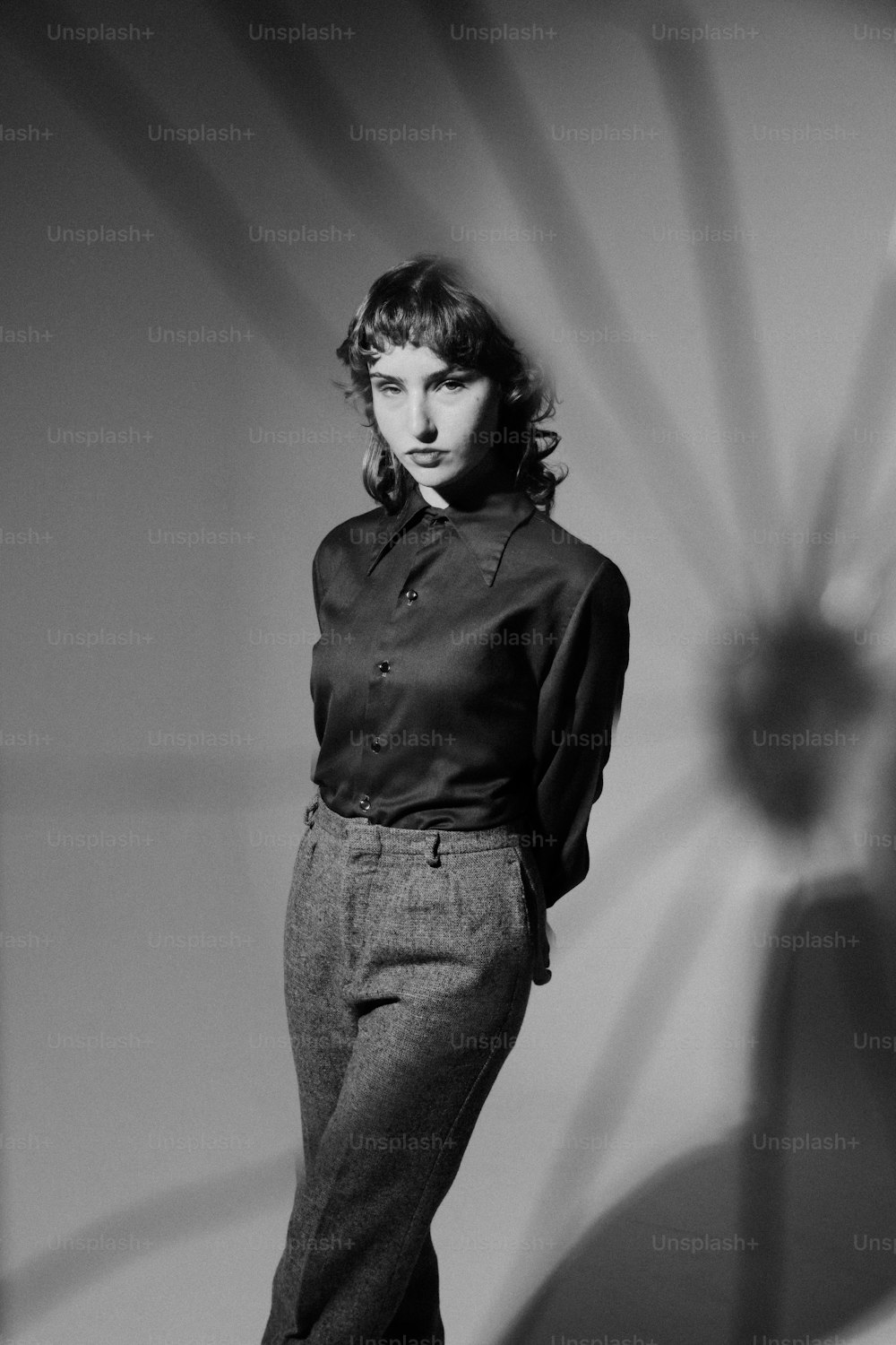 Una foto en blanco y negro de una mujer parada frente a una pared