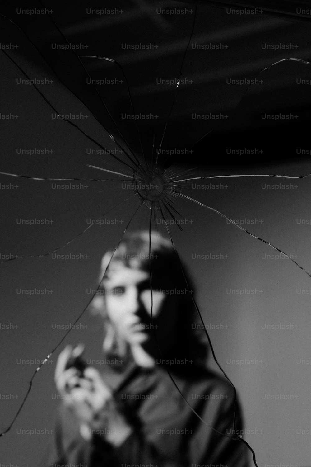 um homem segurando um celular na frente de um vidro quebrado