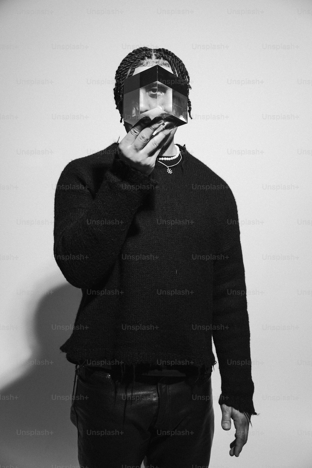 Ein Mann in einem schwarzen Pullover hält eine Zigarette in der Hand
