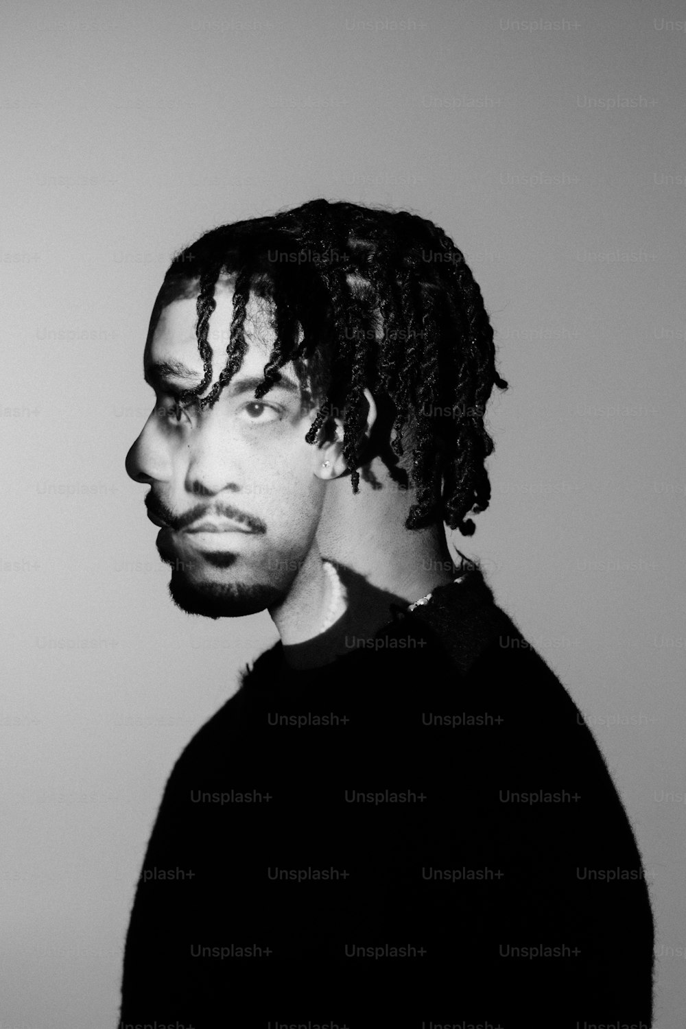 a black and white photo of a man with dreadlocks