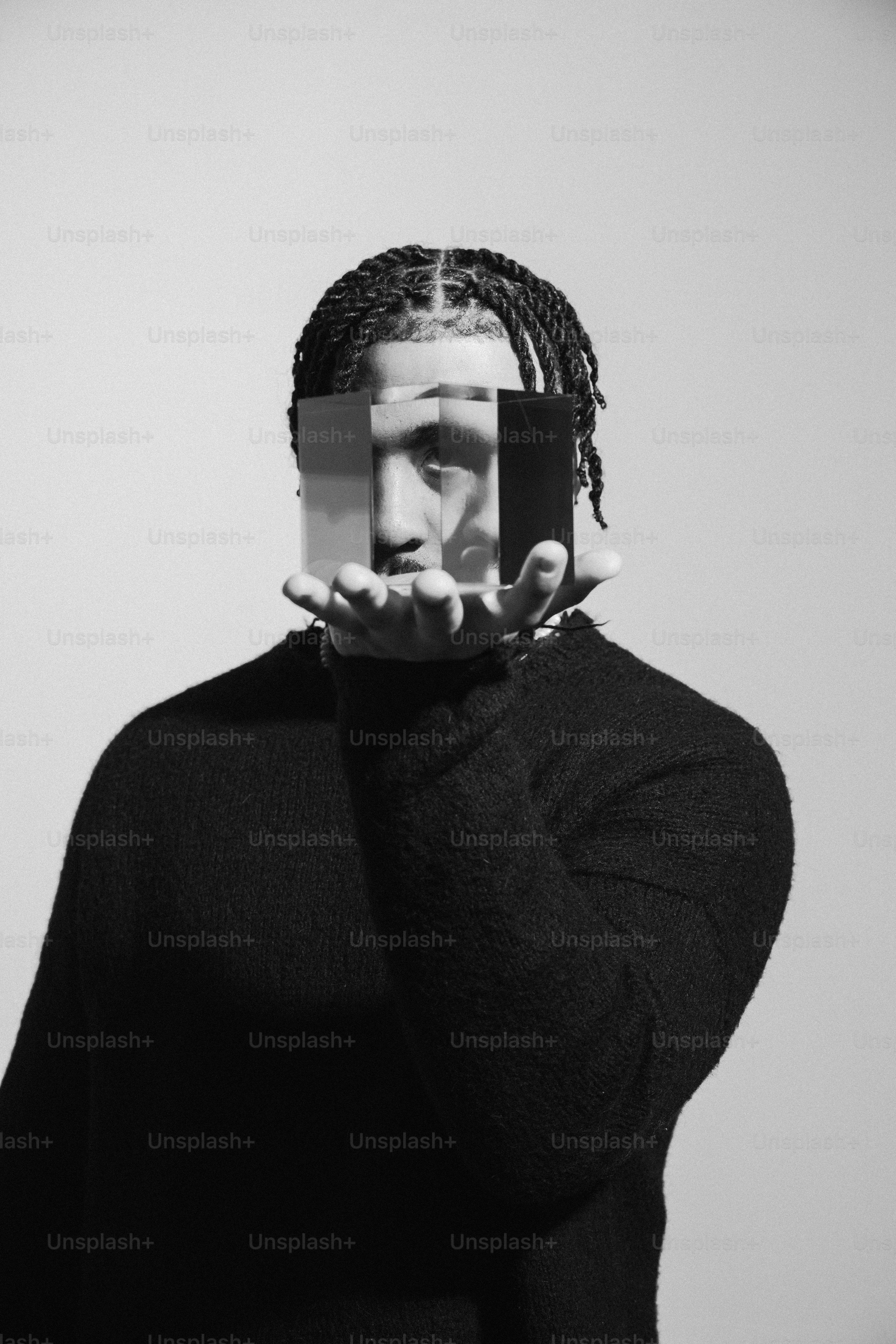 a man with dreadlocks covering his face with a piece of paper