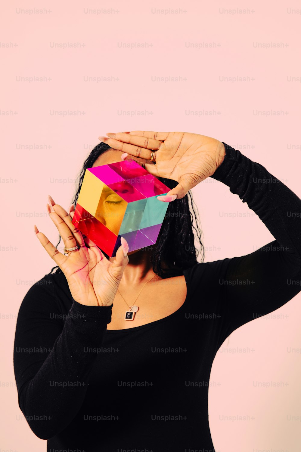 une femme tenant un cube coloré devant son visage