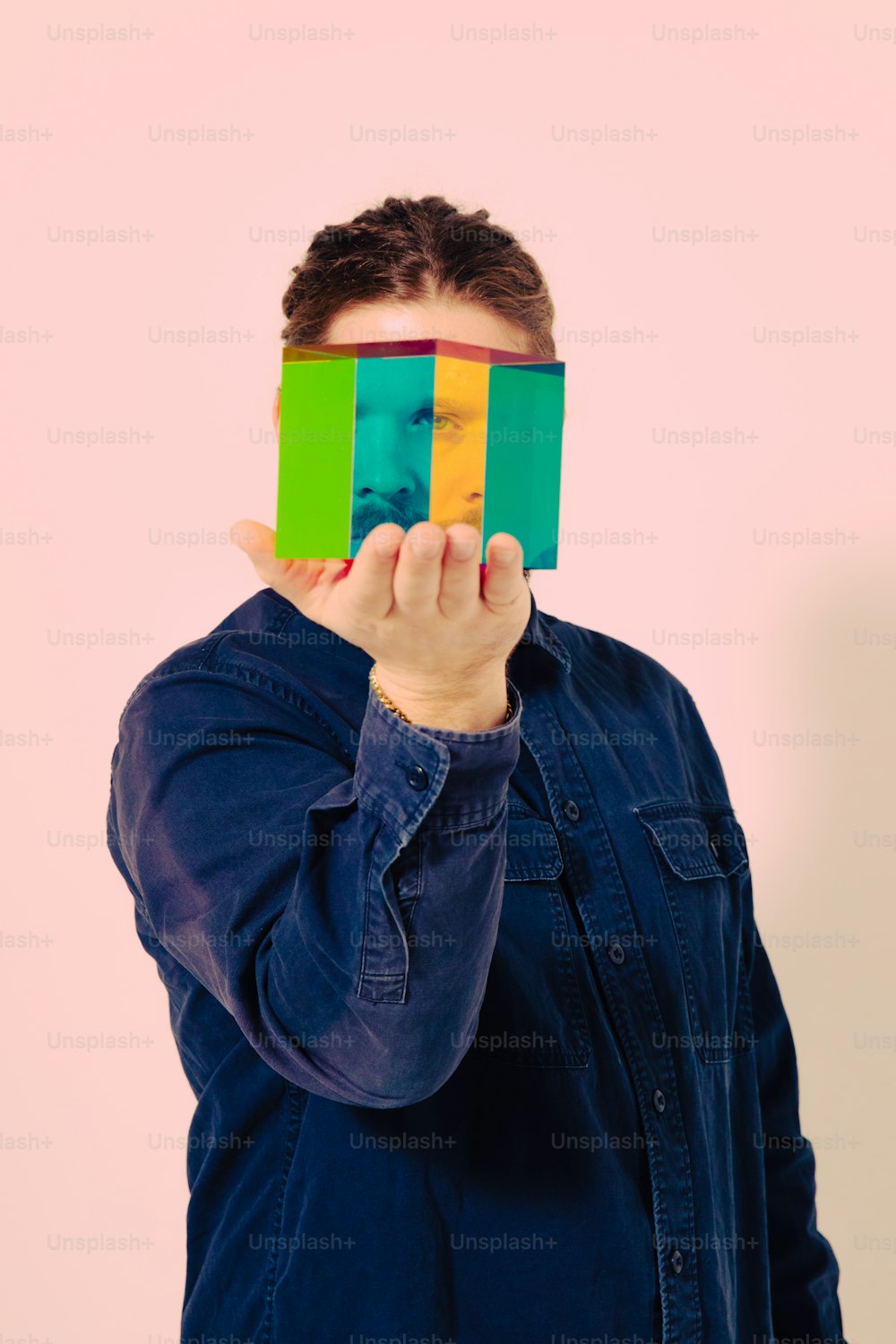 ein Mann, der sein Gesicht mit einem farbigen Blatt Papier bedeckt