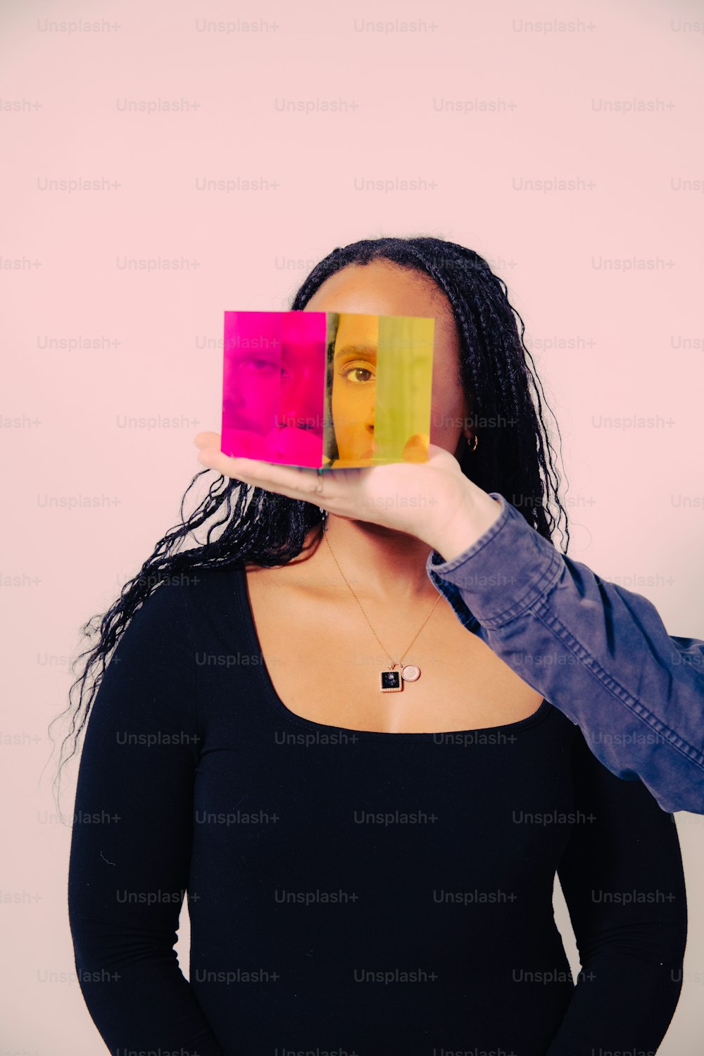 a woman holding a piece of colored paper in front of her face