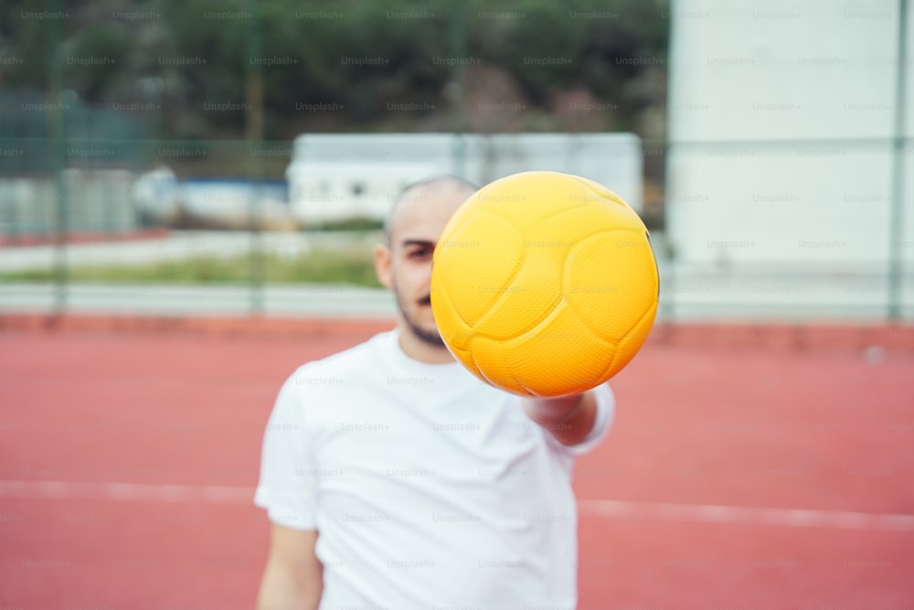 Un hombre sosteniendo una pelota amarilla en una cancha de tenis