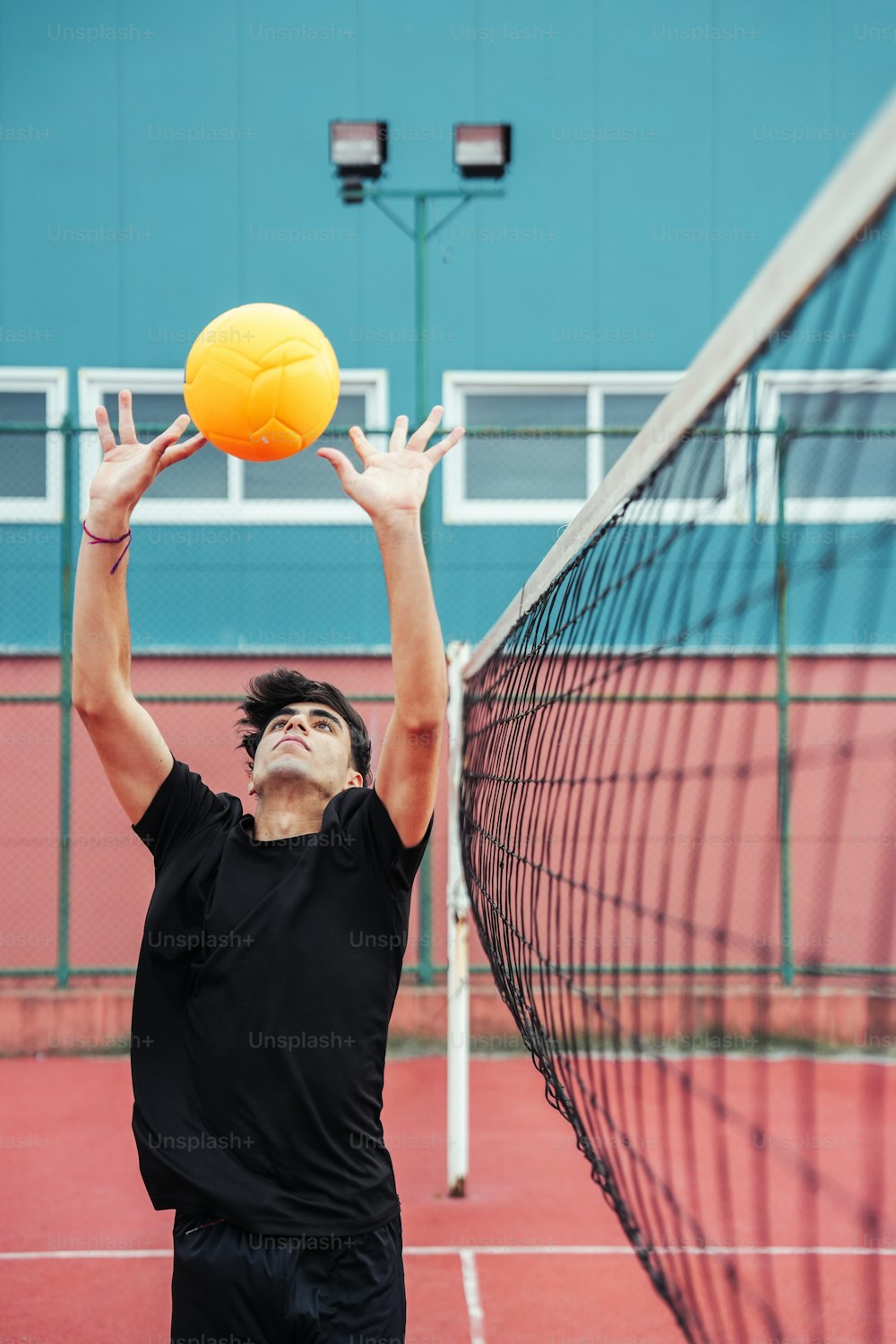 a man reaching up to hit a yellow ball