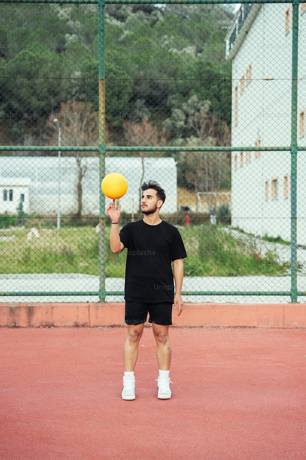 黄色いボールを持ってテニスコートに立つ男性