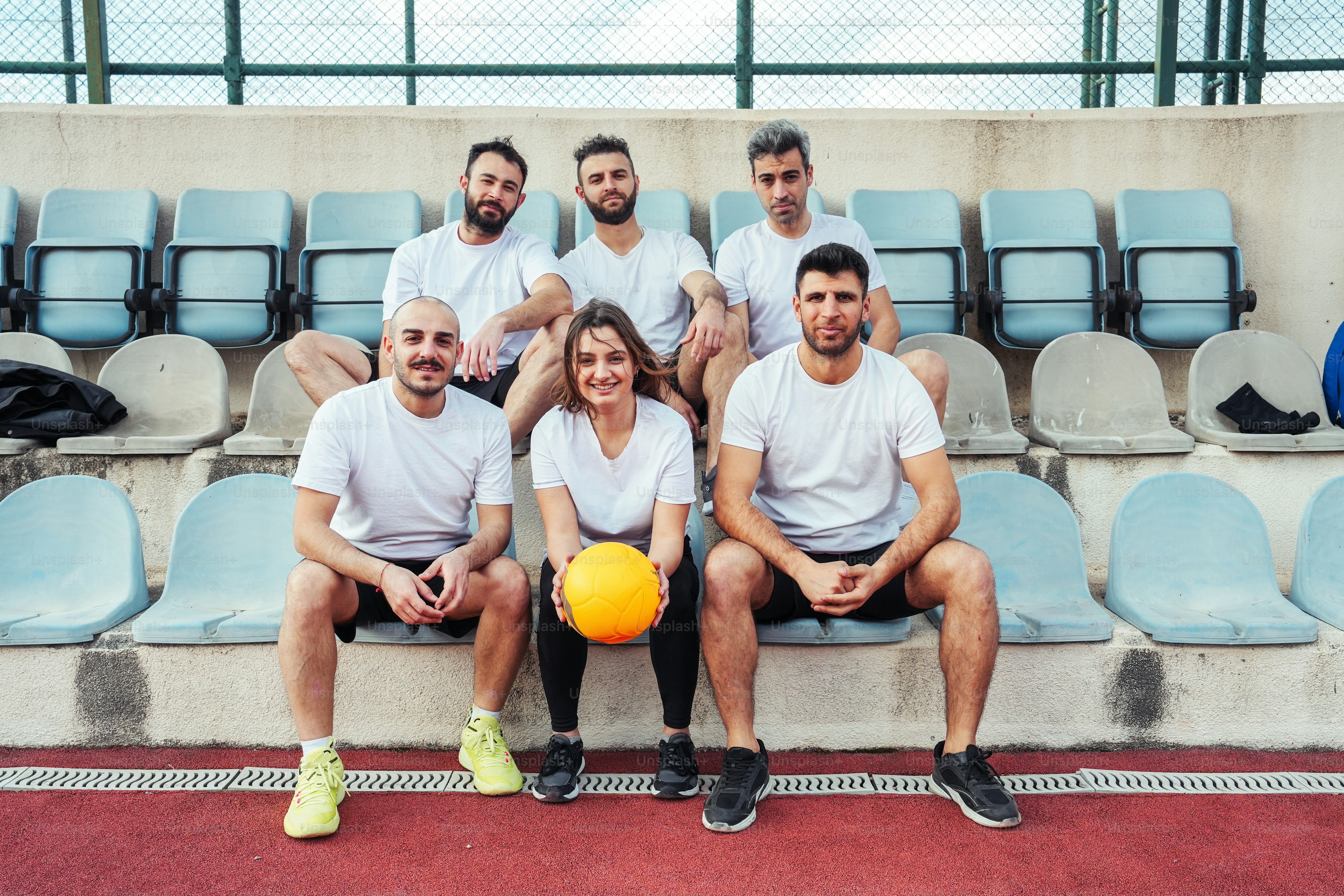 a group of people sitting on a bench with a ball