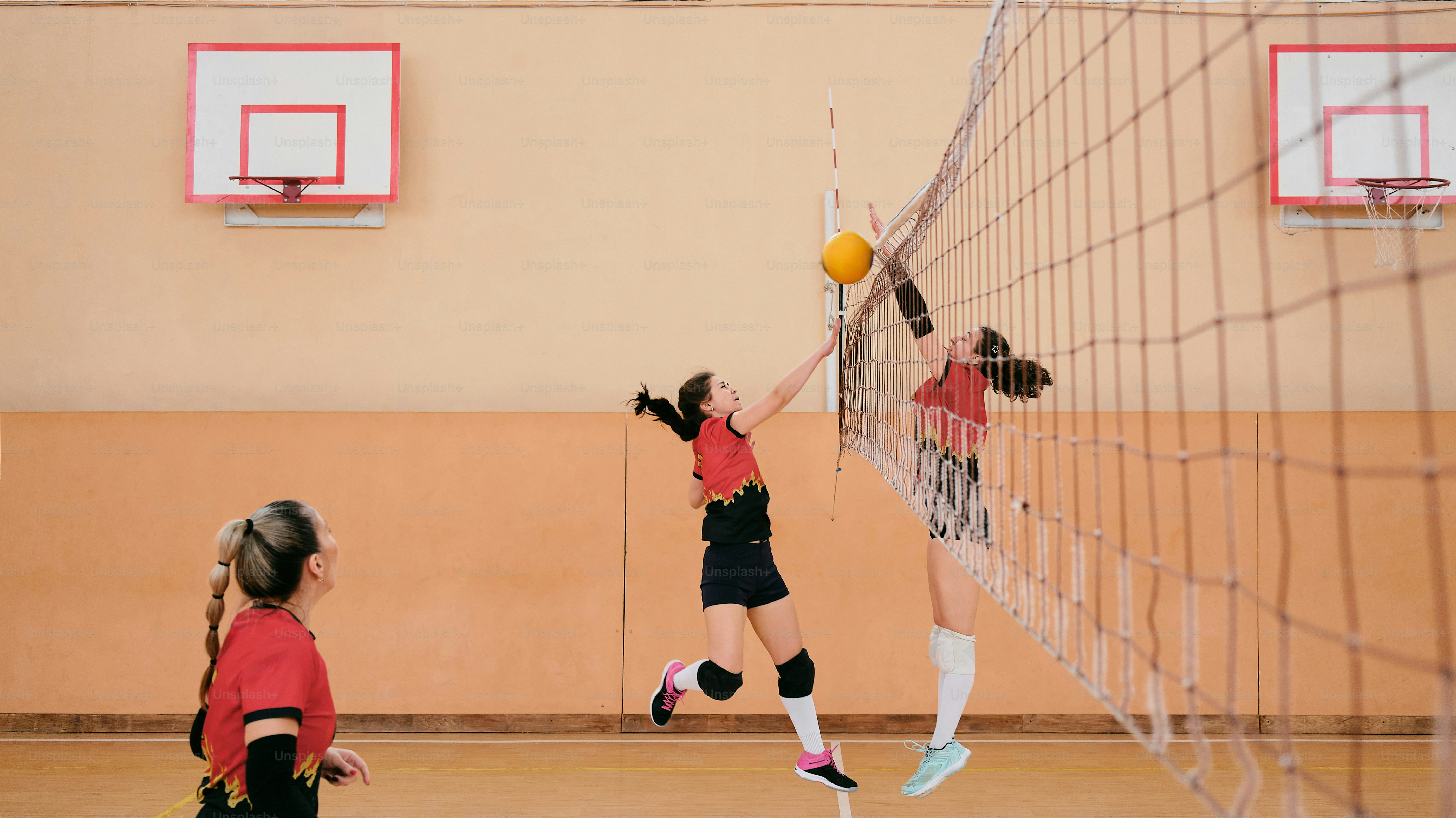um grupo de meninas jogando uma partida de vôlei
