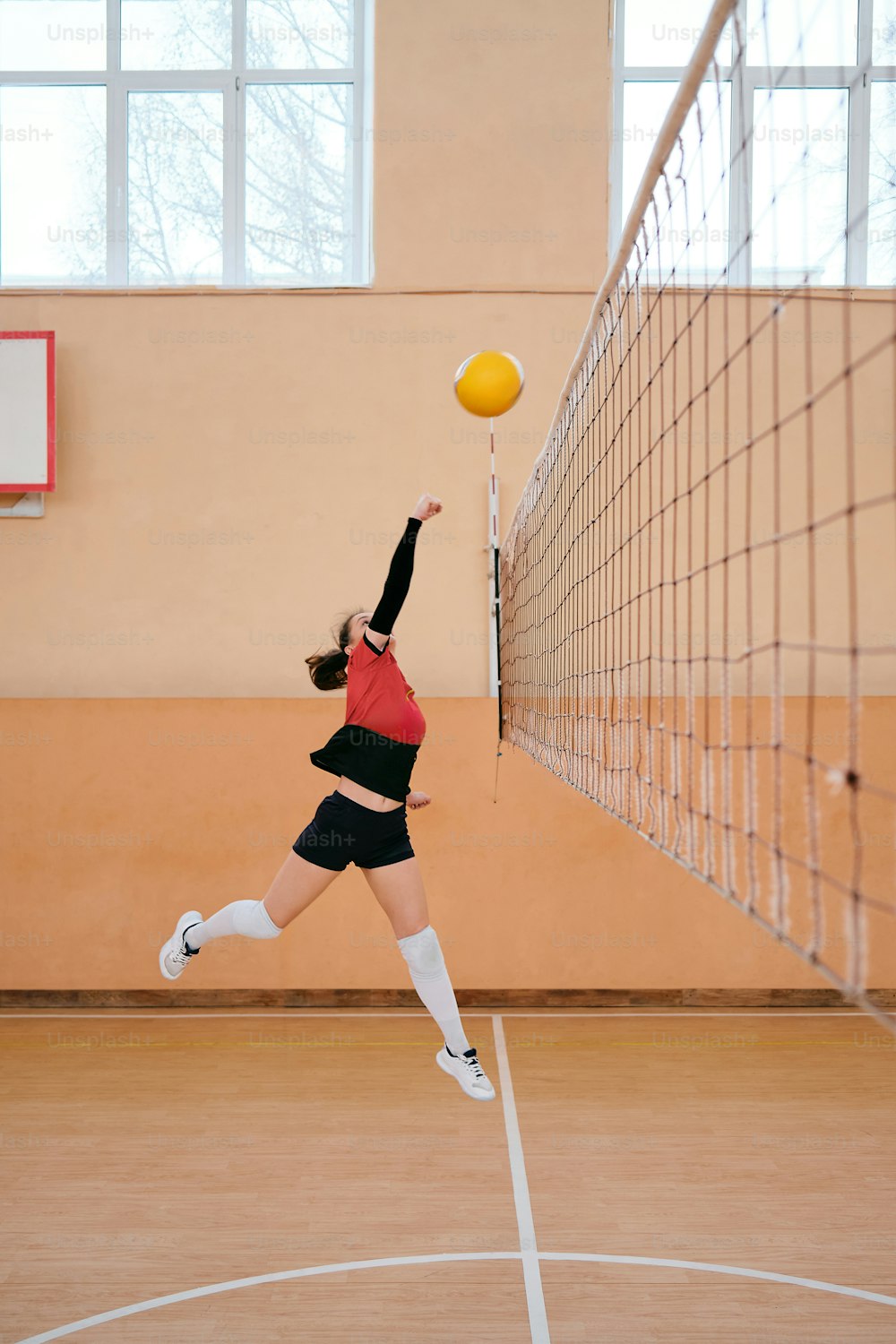 a woman jumping up to hit a volley ball