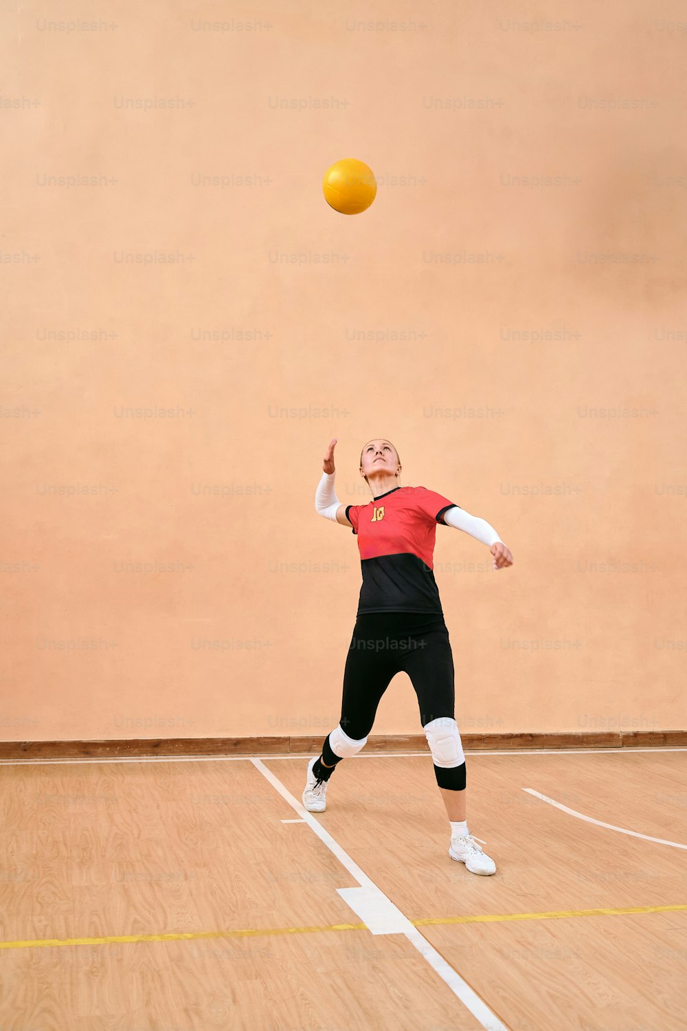 a woman in a red shirt is playing with a yellow ball