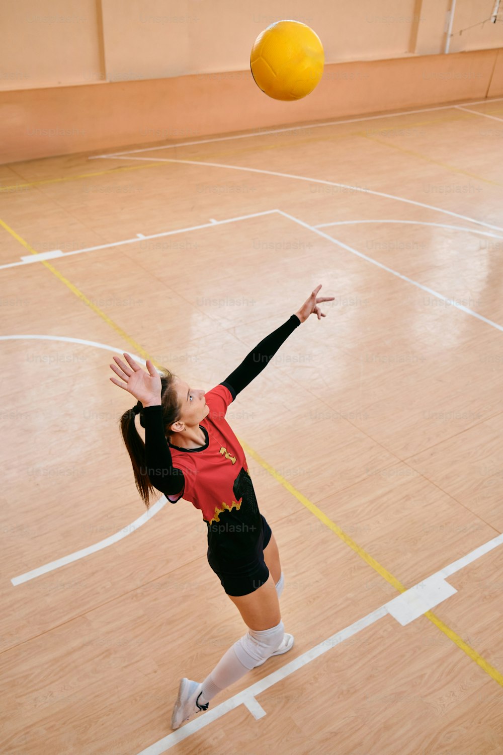 a woman in a red shirt is playing volleyball