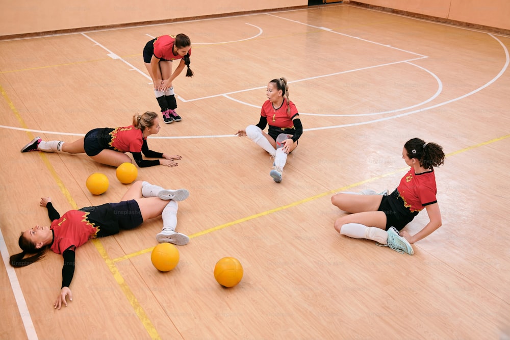 um grupo de mulheres sentadas em cima de uma quadra de basquete