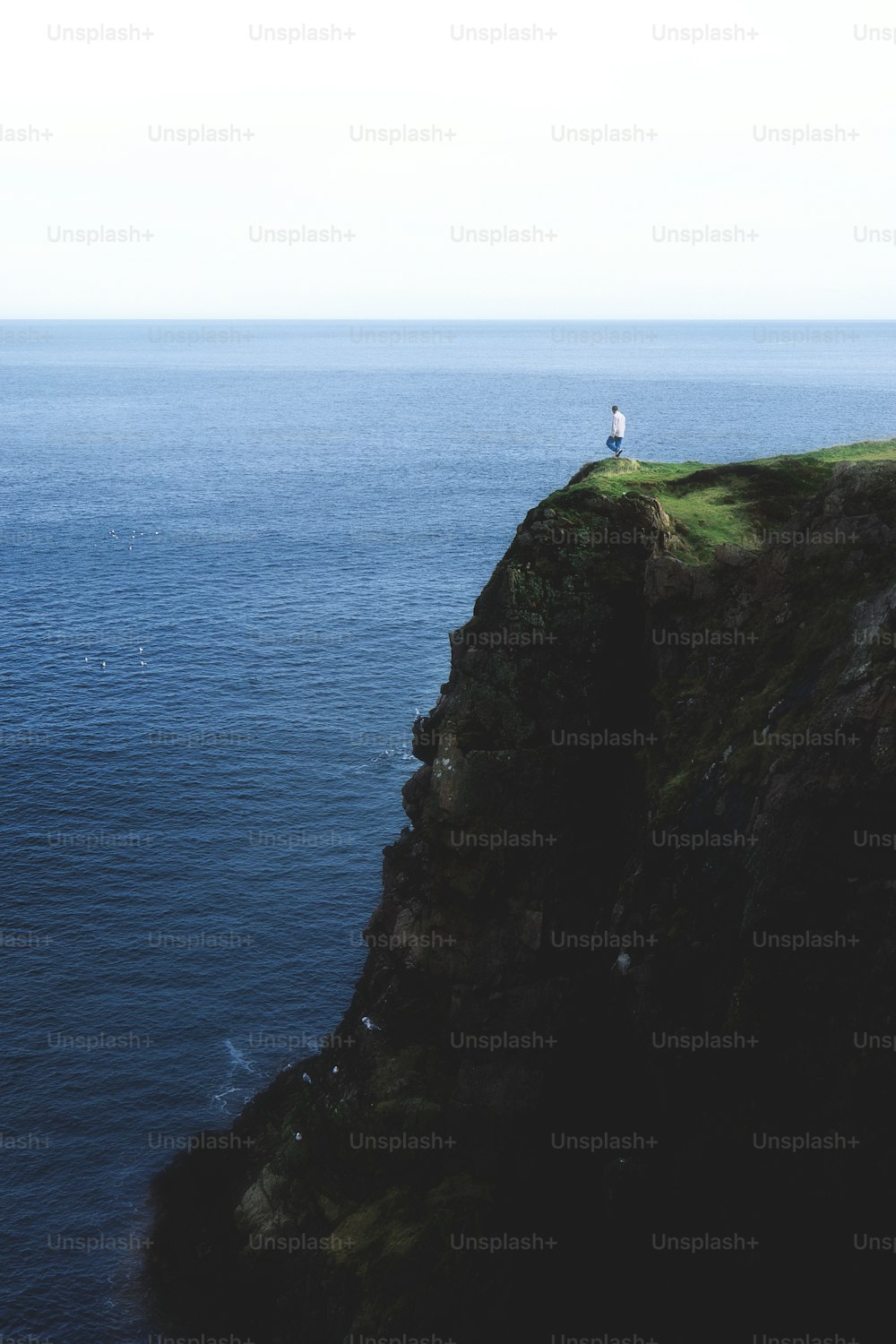 una persona de pie en un acantilado con vistas al océano