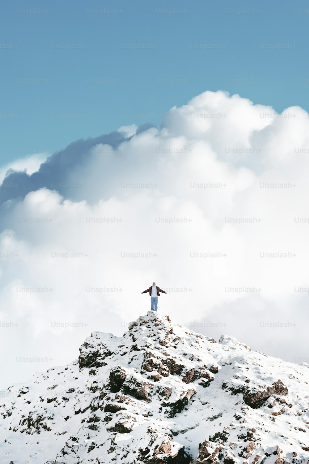 eine Person, die auf dem Gipfel eines schneebedeckten Berges steht