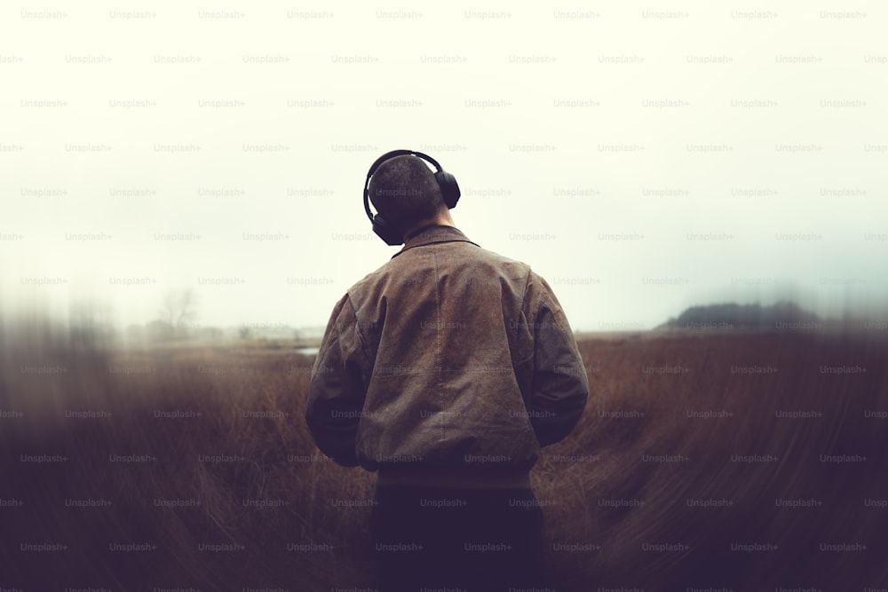 a man standing in a field with headphones on