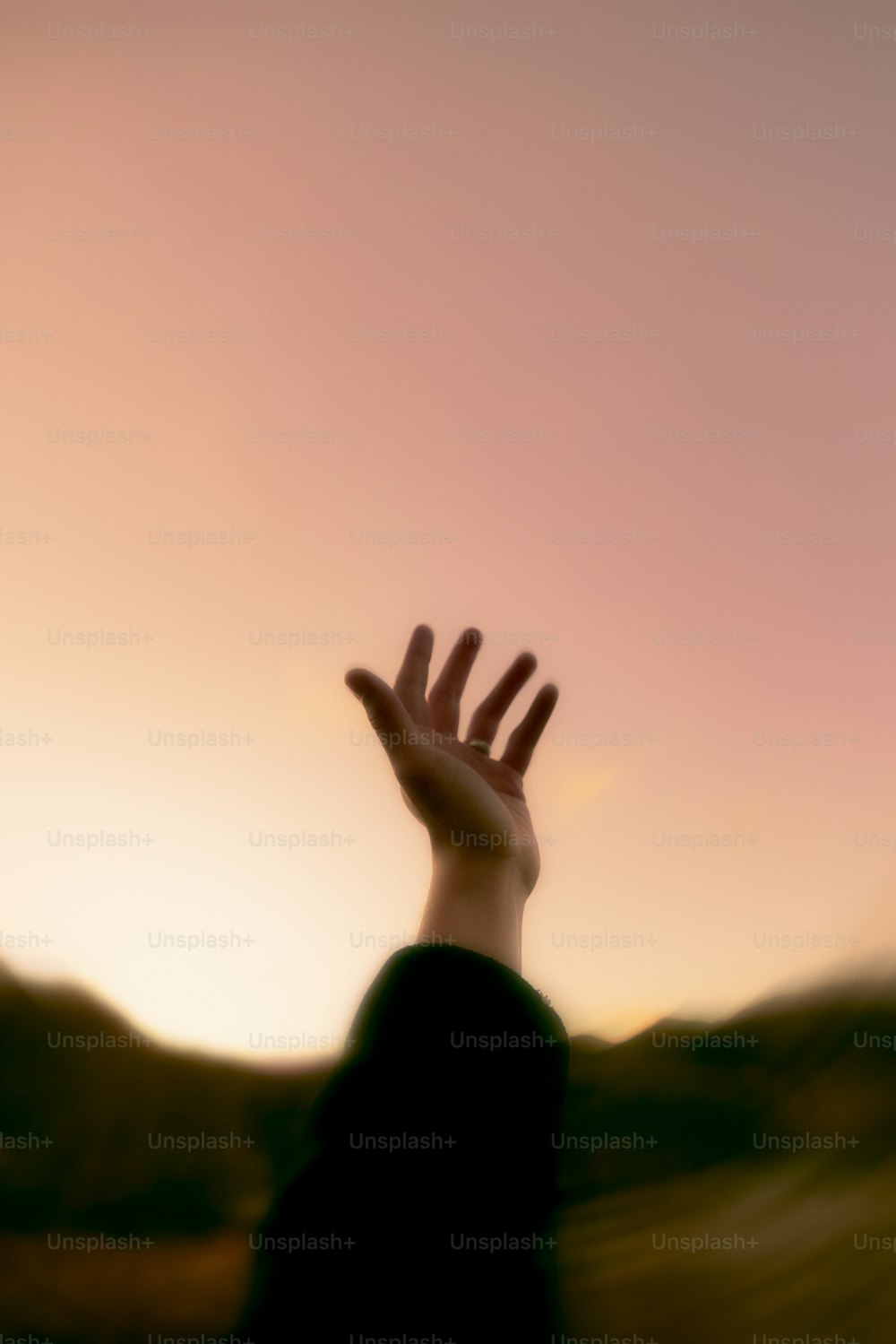 uma foto desfocada de uma mão alcançando o céu