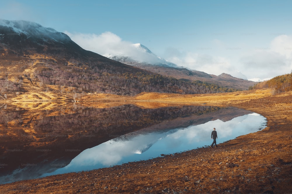una persona in piedi su una collina che domina un lago
