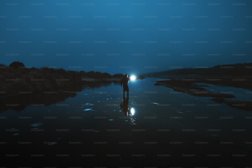 una persona in piedi nel mezzo di uno specchio d'acqua di notte
