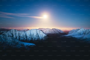 a full moon is seen over a mountain range