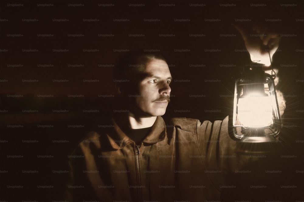 Un hombre sosteniendo una linterna en la oscuridad