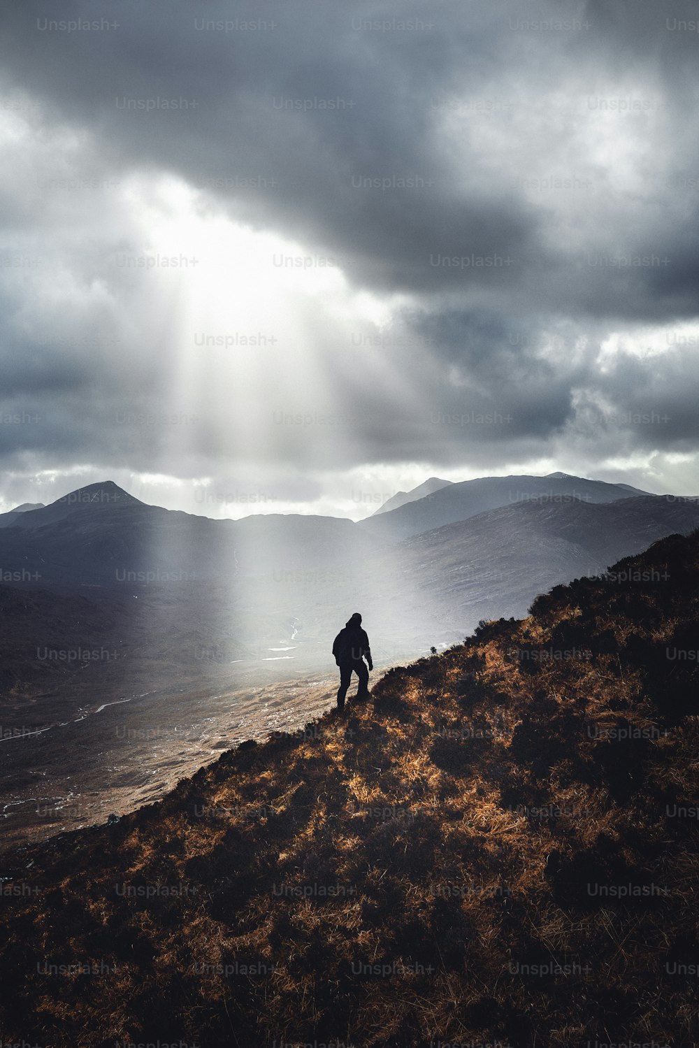 un hombre parado en la cima de una colina bajo un cielo nublado