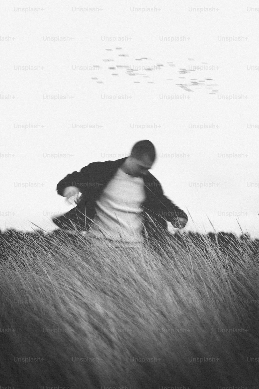 背の高い草むらの中を歩く男性の白黒写真
