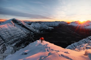 Un par de personas de pie en la cima de una montaña cubierta de nieve